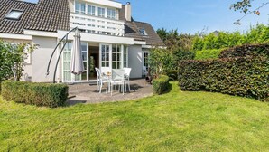 A house with a patio, white furniture, and a garden.