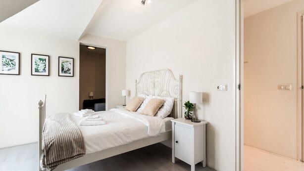 A modern bedroom with a bed, bedside tables, and a door.