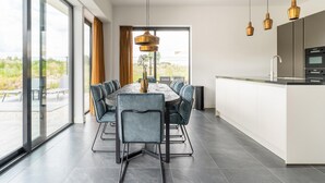 A modern kitchen with a dining area, large windows, and a view of the outdoors. - Villa in Zeewolde Near Flevostrand Beach (Zeewolde)