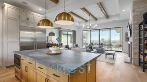 A modern kitchen with a large island, stainless steel appliances, and wooden cabinetry. - ***NEW*** INFINITY POOL | HOT TUB | Views | Pool Table | Fire Pit | 16 Queen Beds (Austin)