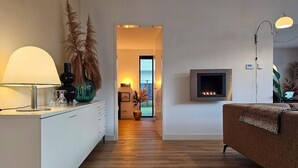 Una sala de estar moderna con chimenea, un sofá y un televisor montado en la pared.