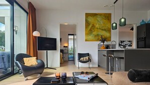 Una sala de estar moderna con un sofá de cuero negro, una mesa de centro y un ventanal con cortinas.