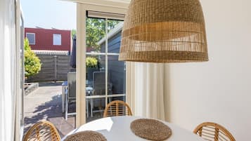 Uma área de refeições com mesa redonda, jogos americanos de vime e luminária pendente trançada.