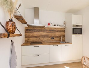 A modern kitchen with wooden cabinetry, a built-in stove, and a hanging vase with dried plants.