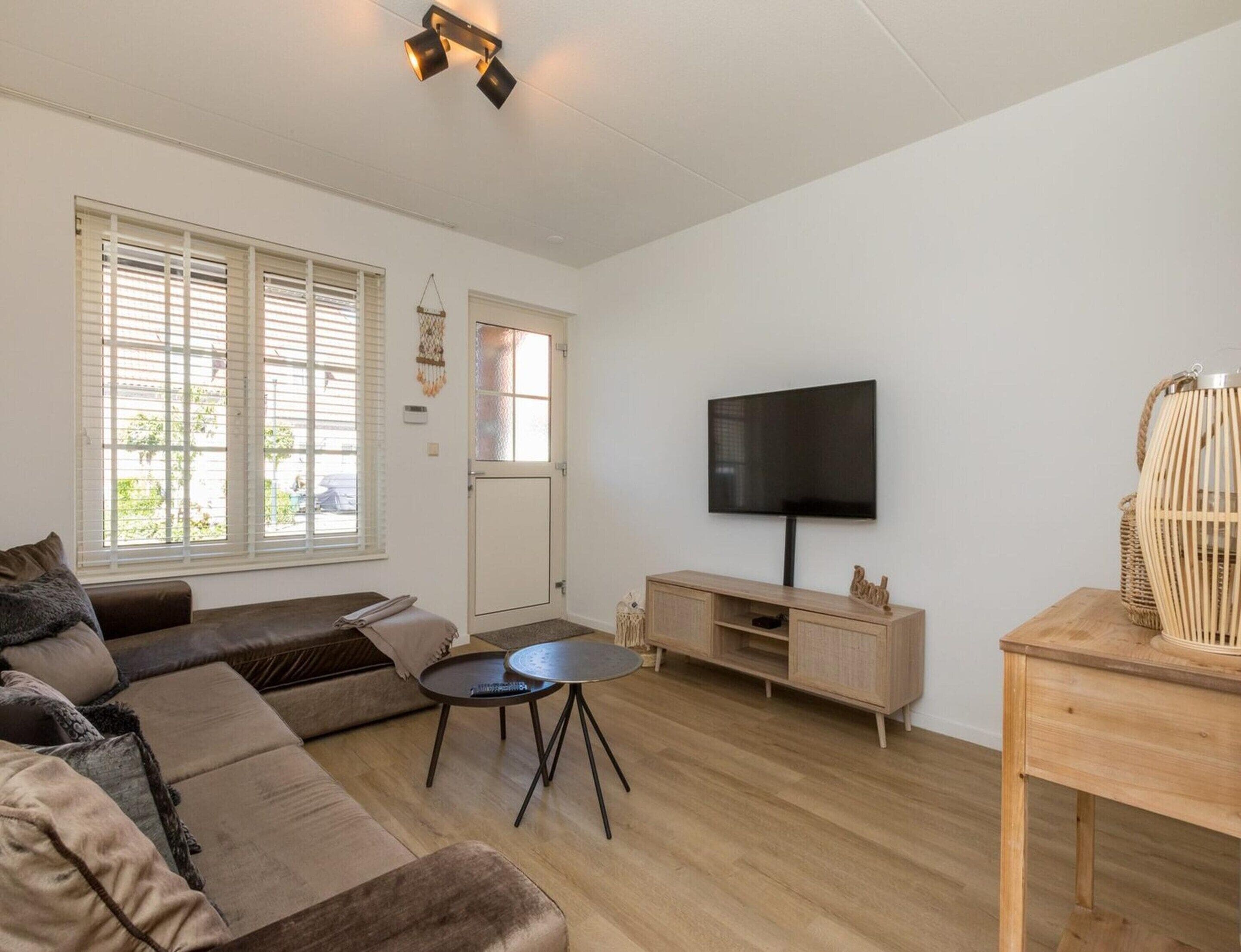 Uma sala de estar moderna com sofá, mesa de centro, TV e mesinha de madeira.