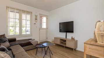 Uma sala de estar moderna com sofá, mesa de centro, TV e mesinha de madeira.