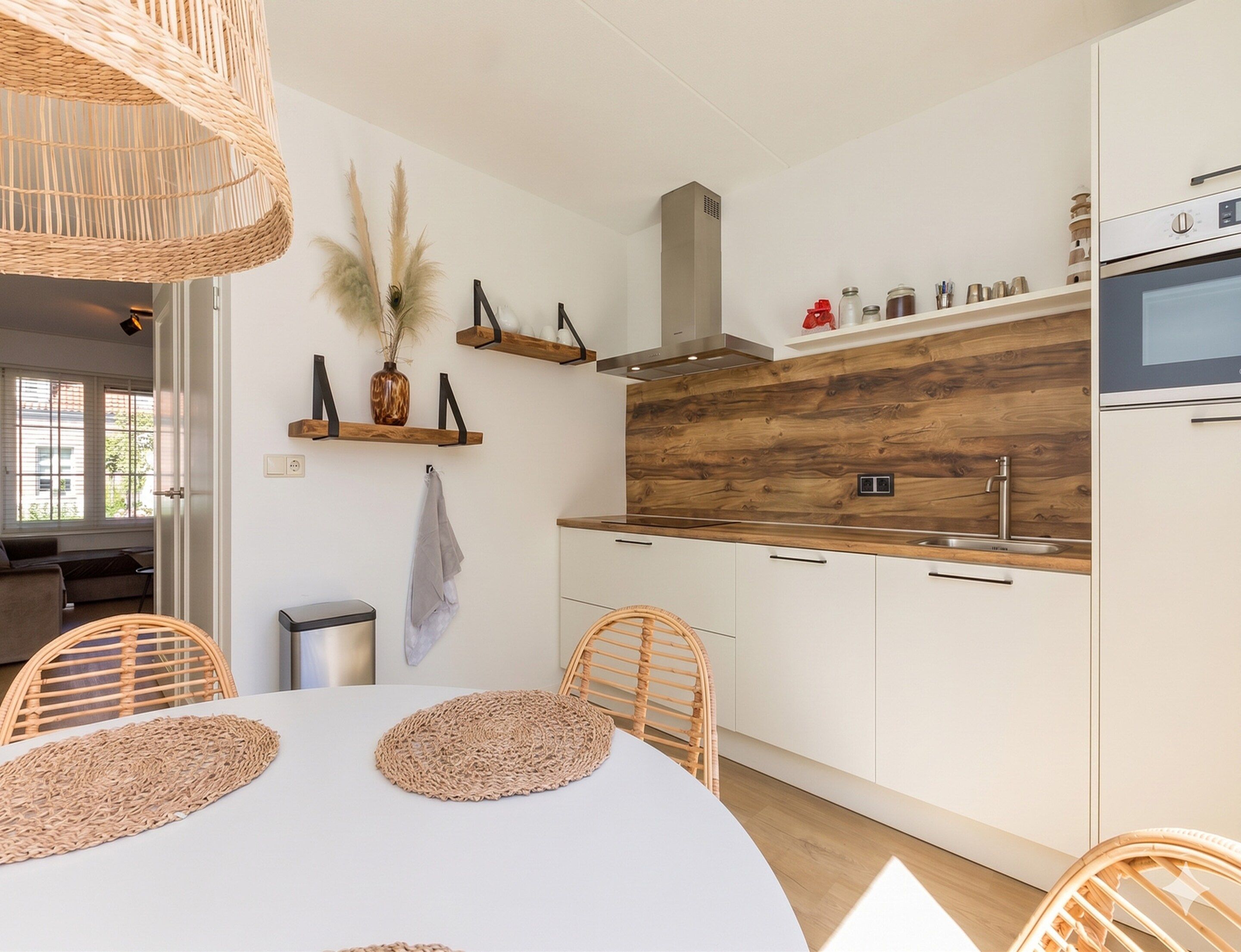 Een moderne keuken met witte kasten, een houten spatwand en een ingebouwde oven.