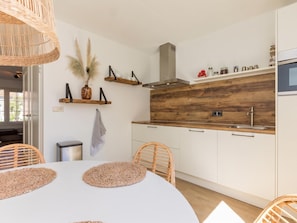 Une cuisine moderne avec des meubles blancs, un pare-feu en bois et un four encastré.
