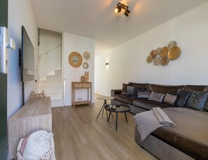 A modern living room with a sofa, a coffee table, a TV, and a staircase. - Holiday Home in Domburg Near the Beach (Domburg)