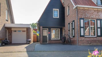 Uma rua residencial com casas, uma garagem e uma bicicleta.