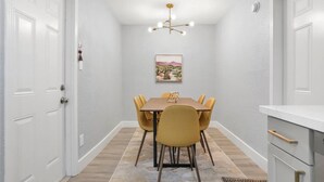 Un coin repas comprenant une table et des chaises, un luminaire au plafond et un tableau accroché au mur.