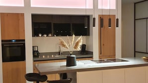 Una cocina moderna con armarios de madera, una isla central, taburetes de bar e iluminación colgante.
