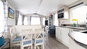 A compact RV interior with a dining area, kitchenette, and a small seating space. - Chalet in Renesse Near Sandy Beaches (Renesse)
