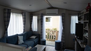 A living room with a sofa, a coffee table, a TV, and a bookshelf. - Chalet in Renesse Near Sandy Beaches (Renesse)