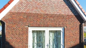 Un bâtiment en briques, doté d’un toit à pignon et d’une double porte avec des panneaux de verre dépoli.
