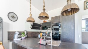 A modern kitchen with a central island, stainless steel appliances, and pendant lighting.