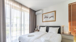 A hotel room with a large bed, a nightstand, a lamp, and a painting on the wall.