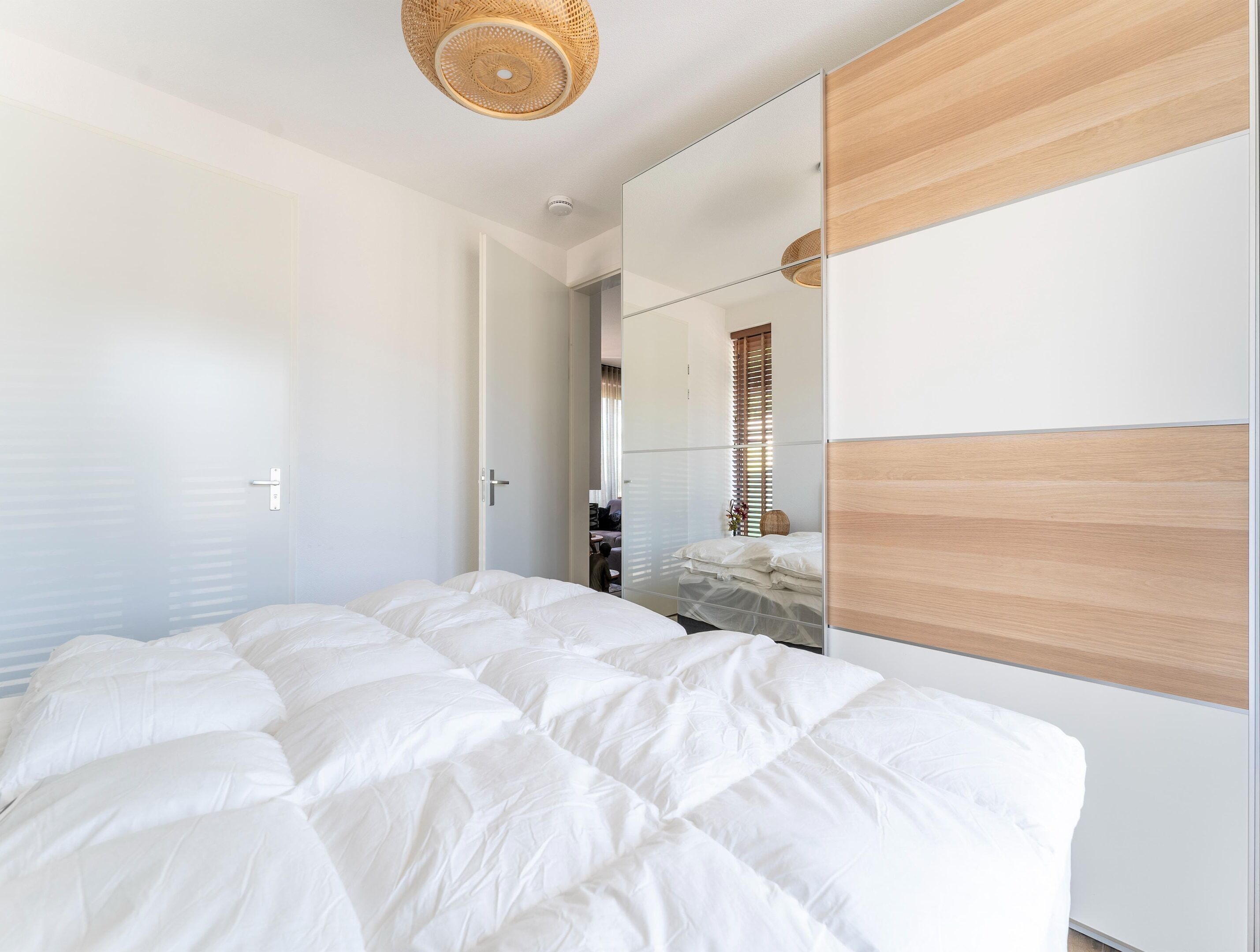 Un dormitorio con una cama grande, un cabecero de madera, un espejo y una lámpara en el techo.