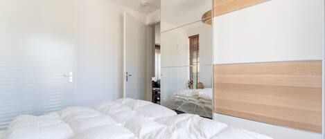Un dormitorio con una cama grande, un cabecero de madera, un espejo y una lámpara en el techo.