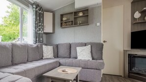 Ein modernes Wohnzimmer mit einem grauen Ecksofa, einem kleinen Holztisch und einer integrierten TV-Konsole.