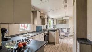 Eine moderne Küche mit Kochinsel, integrierten Geräten und einem Essbereich mit Sofa und Tisch.