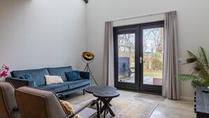 Een moderne woonkamer met een blauwe bank, een kleine ronde tafel en een vloerlamp.
