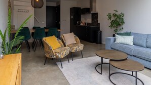 Een moderne woonkamer met een bank, twee fauteuils, een salontafel en een eethoek met een tafel en stoelen.