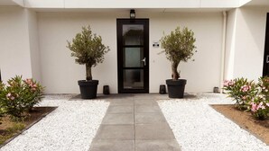 A modern building with a white exterior, a black door, and two potted trees in front. - Villa in Zeewolde With Private Terrace (Zeewolde)