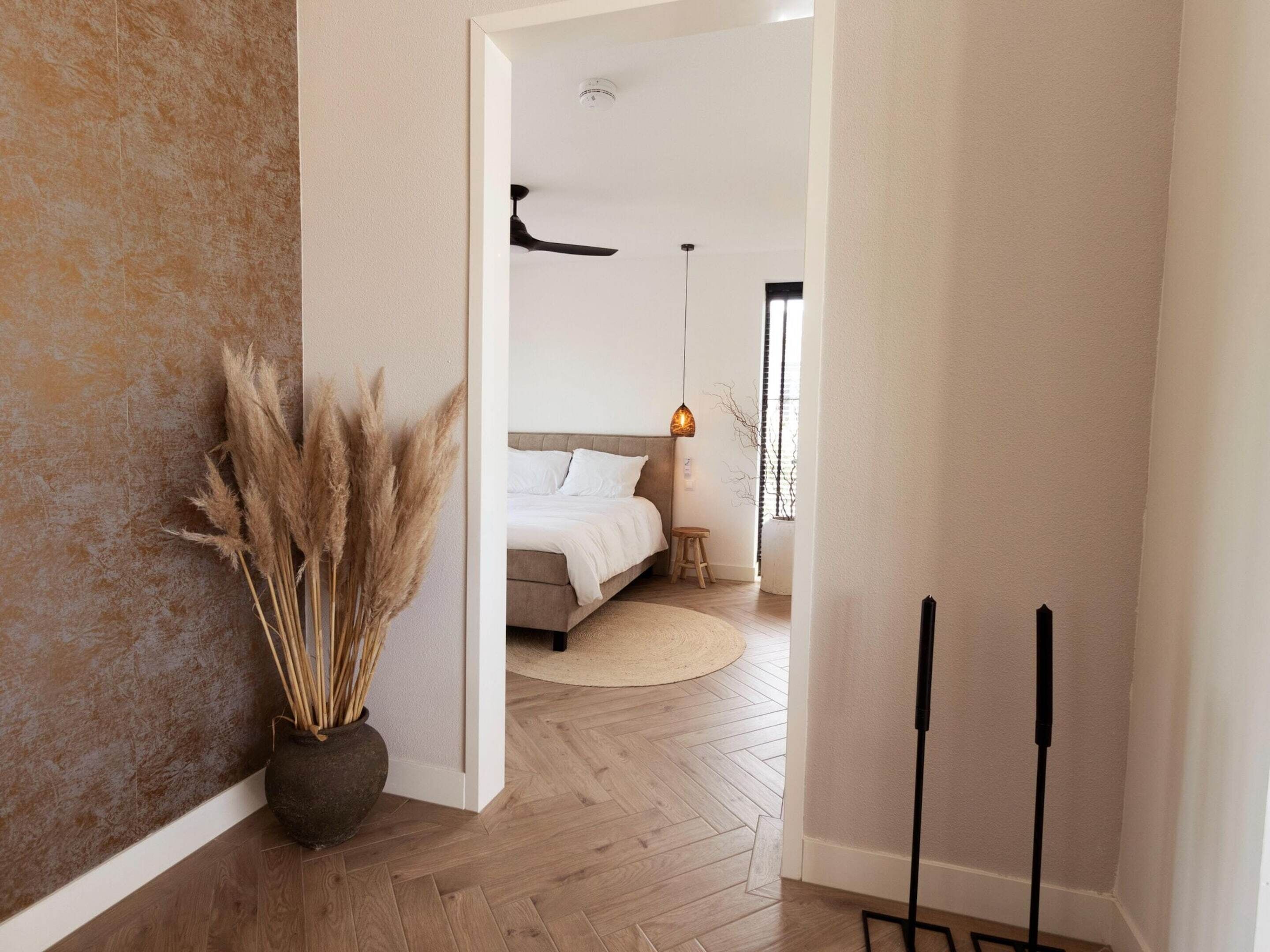 A modern bedroom with a bed, bedside table, and a hanging light fixture.