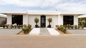 A modern building with a symmetrical facade, large black doors, and potted plants in front. - Villa in Zeewolde With Private Terrace (Zeewolde)