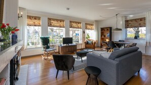 A living room with a sofa, chairs, a TV, and a dining area with a table and chairs. - Home Zoutelande Near Beach (Zoutelande)