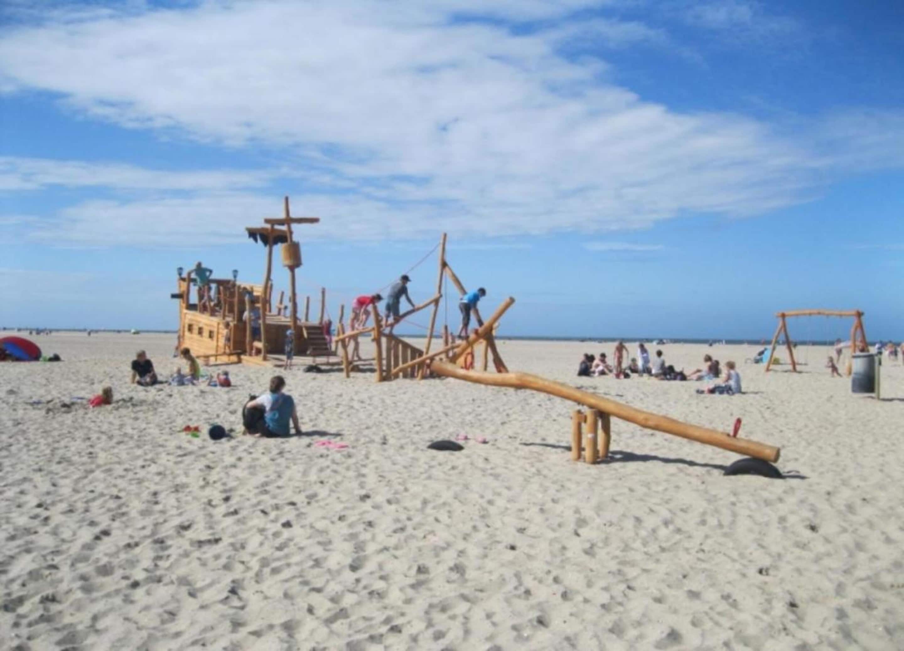 A beach with wooden play structures and a long wooden beam.