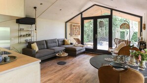 A spacious living area with a large sofa, a dining table, and a kitchen area with a sink and counter. - Cosy Holiday Home With Private Sauna (Wissenkerke)