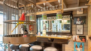 A bar area with a birdcage, stools, and a counter with bottles. - Romantic Chalet Near Wilhelminadorp (Wilhelminadorp)