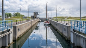 A canal with a boat docked at a lock, surrounded by a concrete lock structure, a small building, and a grassy area. - Romantic Chalet Near Wilhelminadorp (Wilhelminadorp)