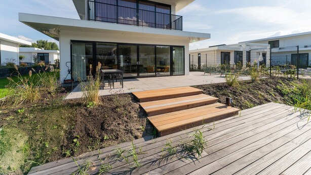 A modern two-story house with a balcony, a patio with a wooden deck, and a garden area. - Villa in Zeewolde for 6 Person (Zeewolde)