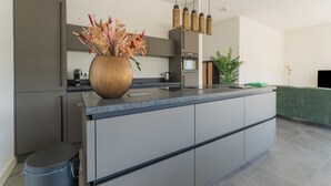 A modern kitchen with a central island, stainless steel appliances, and a hanging light fixture. - Villa in Zeewolde for 6 Person (Zeewolde)