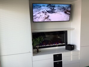 Uma televisão de tela plana fixada acima de um aquário em uma parede branca.