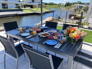 A dining table set outdoors with various dishes, a laptop, and a bouquet of flowers. - Exclusive Villa With Boat Terrace (Zeewolde)
