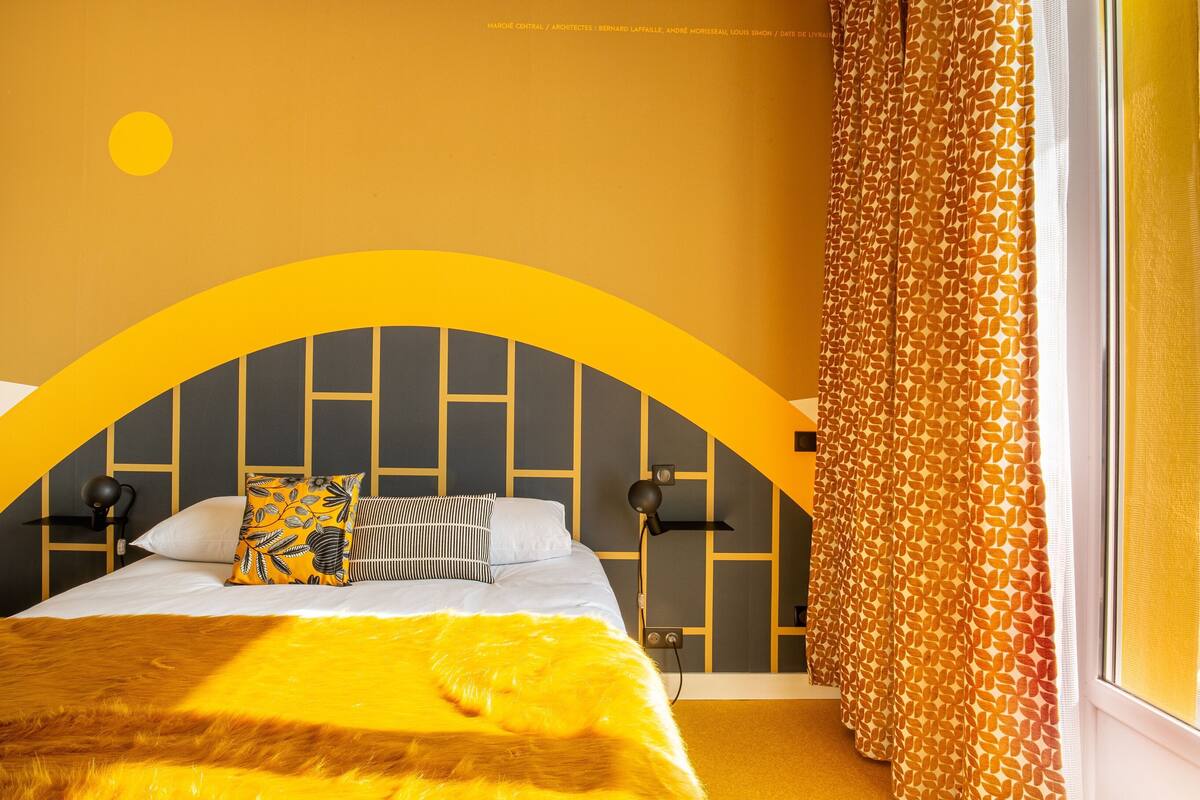 Quarto com uma cama, janela com vista e cortina estampada.