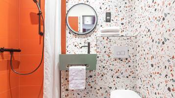 Un baño con ducha, inodoro, lavabo y espejo.