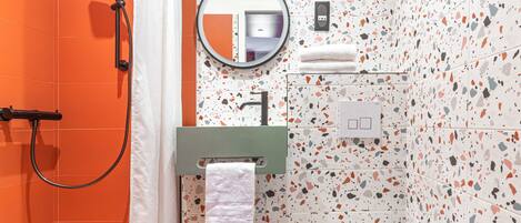 A bathroom with a shower, a toilet, a sink, and a mirror.