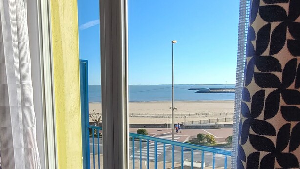 A balcony with a view of the beach, a chair, and a railing. - SEAKUB HOTEL (Royan)