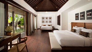 A spacious bedroom with a large bed, a separate sofa, and a dining area with a table and chairs.