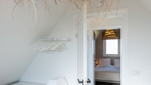 A bedroom with a bed, a bedside table with towels, a hanging light fixture, and a window. - Farmhouse in Zeeland With Saltwater Pool (Oostkapelle)