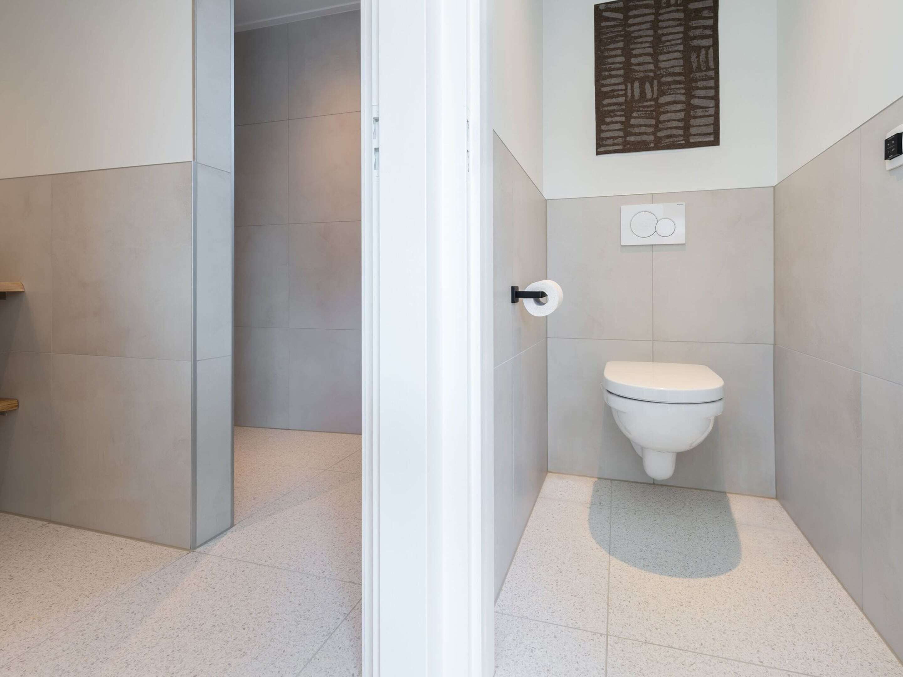 A modern bathroom with a toilet, a towel rack, and a shower area.