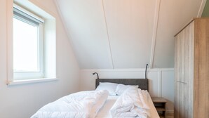 A bedroom with a bed, a window, and a wardrobe. - Holiday Home in Zeeland Near Nature Reserve (Scherpenisse)