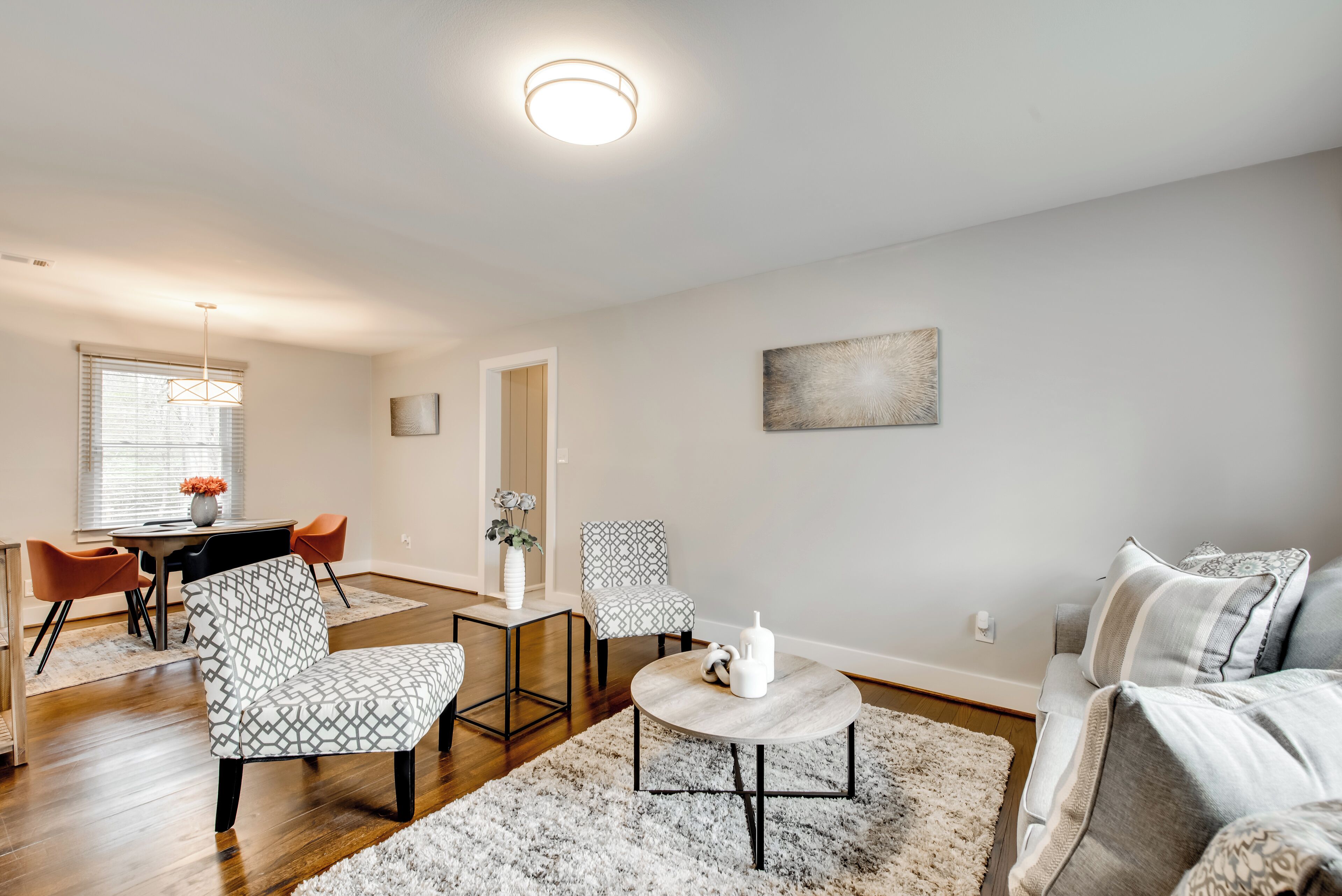 Ein modernes Wohnzimmer mit einer Couch, Sesseln, einem Couchtisch und einem Essbereich mit Tisch und Stühlen.
