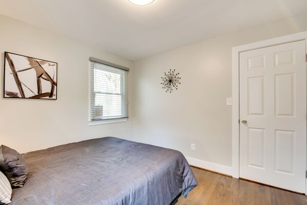 Un dormitorio con cama, ventana, puerta y decoración en la pared.