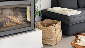 A modern living room with a fireplace, a grey sofa, a woven basket, and a blanket. - Holiday Home Zeeland Near Veerse Meer (Kamperland)